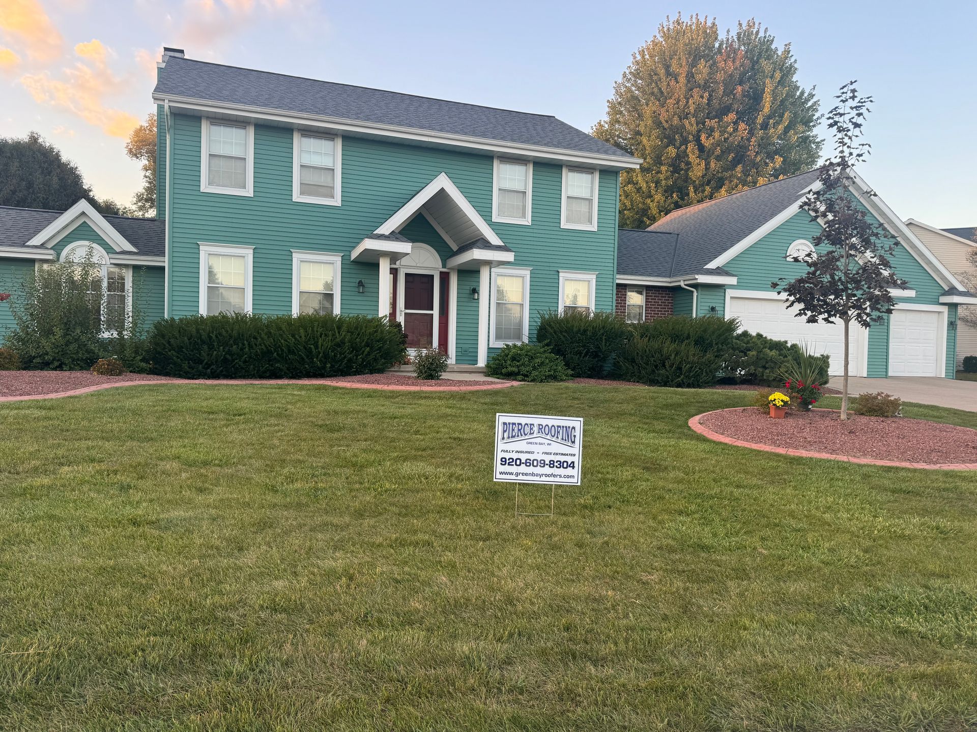 A green house with a sign in front of it.