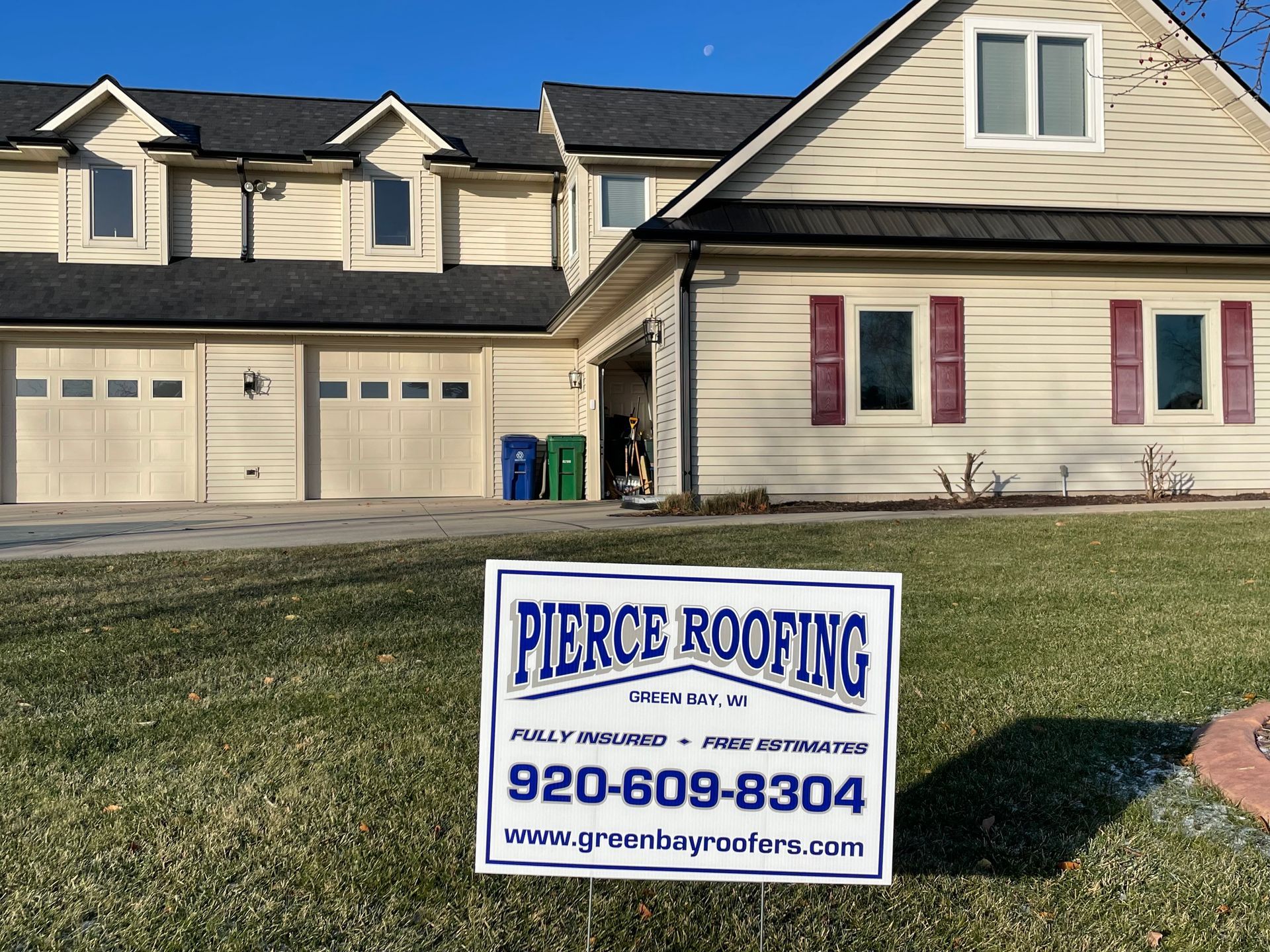 A house with a pierce roofing sign in front of it