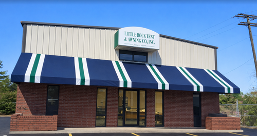 Small brick storefront with blue-and-white striped awnings under a clear blue sky.