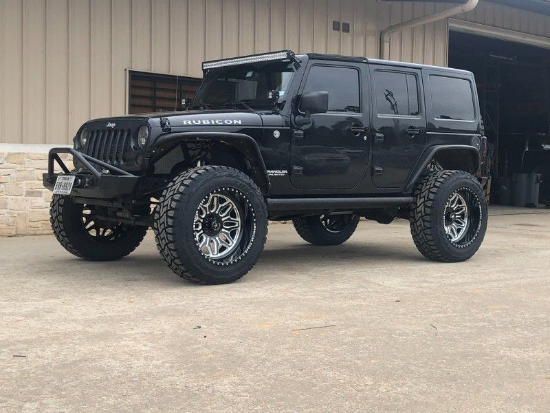 A black jeep is parked in front of a garage.