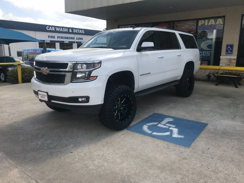 A white suv is parked in a handicapped parking spot.