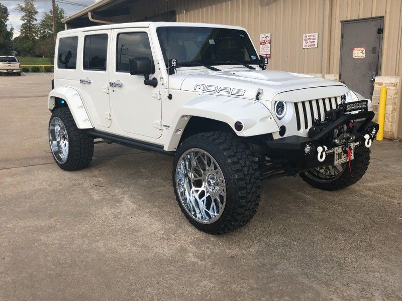 A white jeep is parked in front of a building.