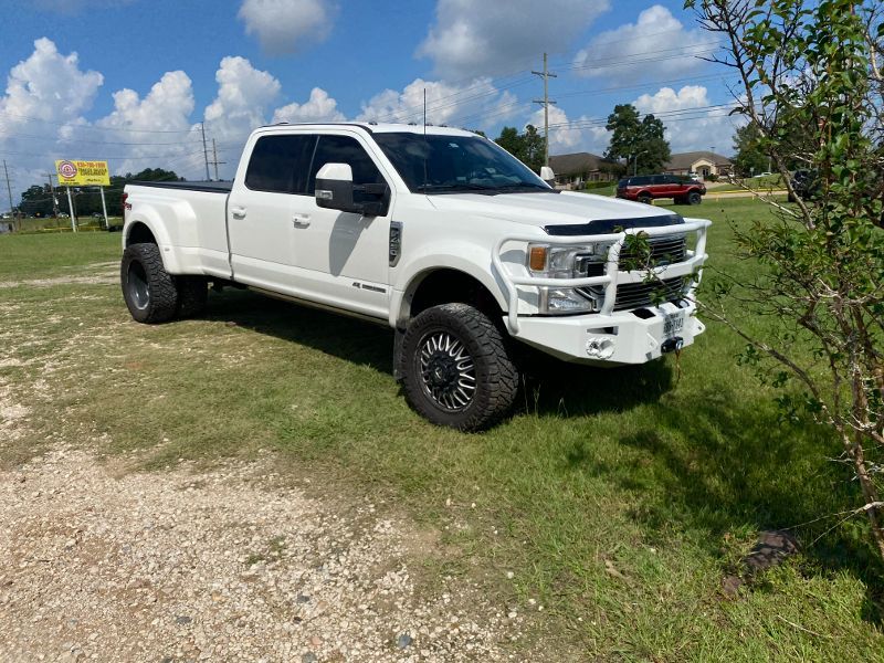 A white pickup truck is parked in a grassy field.