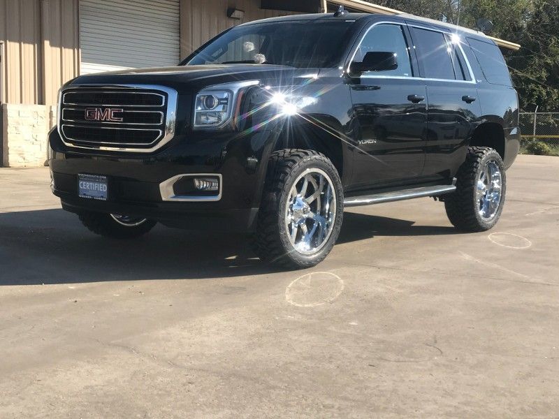 A black suv is parked in a parking lot in front of a building.