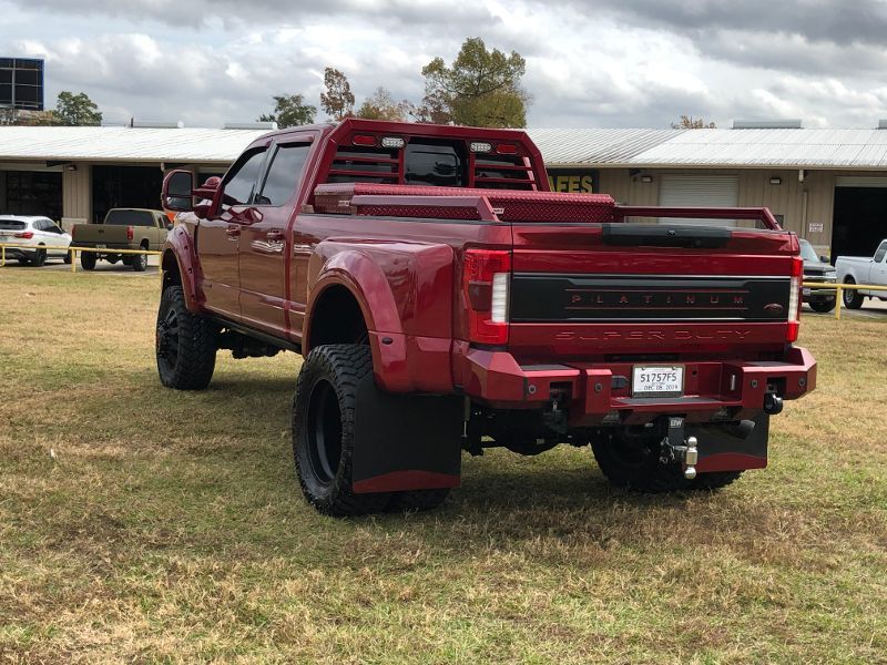 A red truck is parked in a grassy field in front of a building.