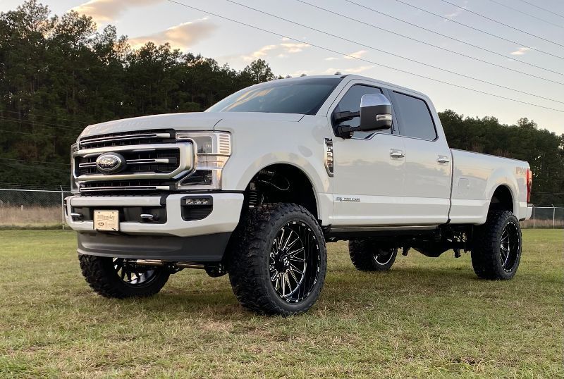 A white ford truck is parked in a grassy field.