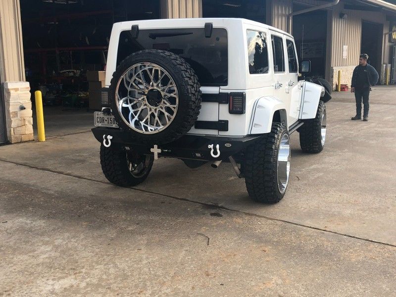 A white jeep with a spare tire is parked in a parking lot.