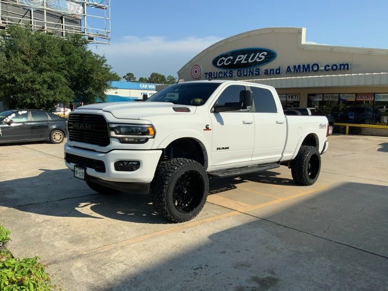 A white truck is parked in a parking lot in front of a store.