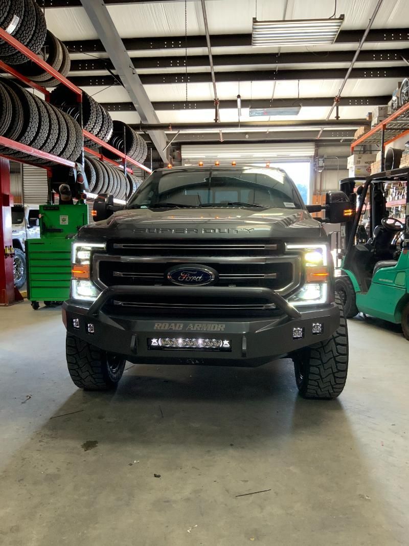 A ford truck is parked in a garage next to a forklift.