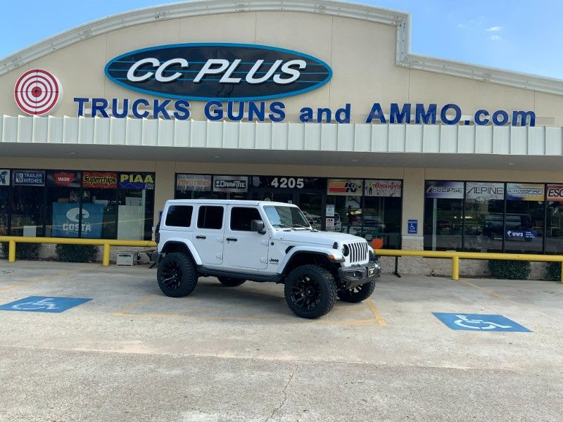 A white jeep is parked in front of a building.