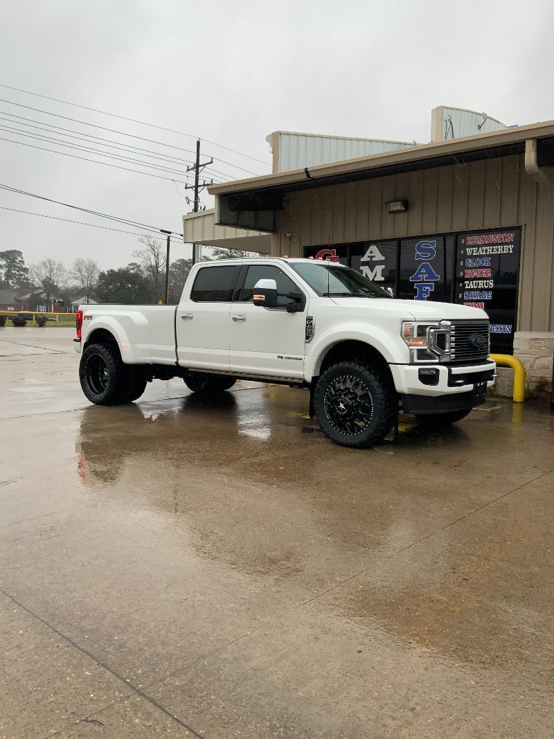 A white truck is parked in front of a building in the rain.