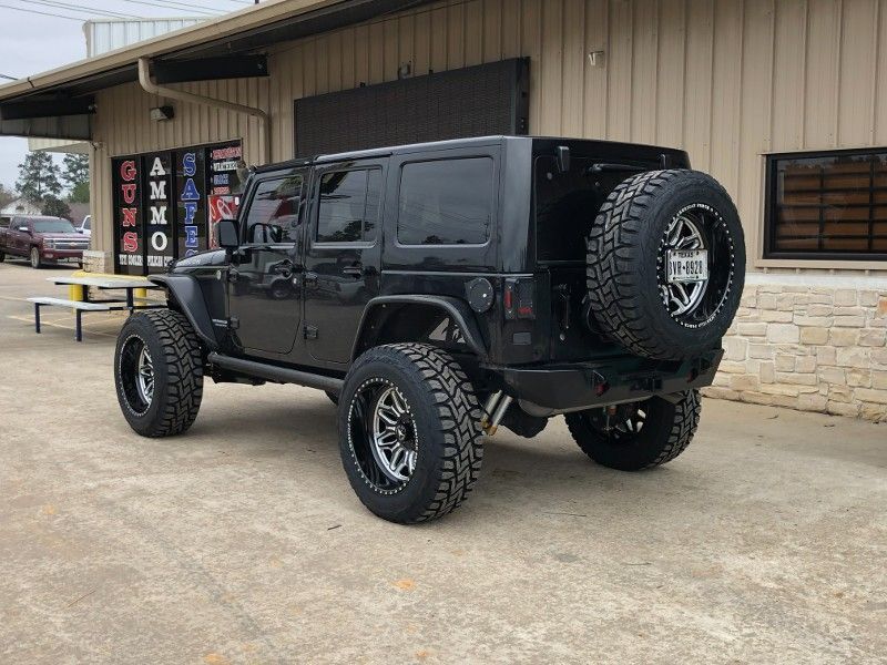 A black jeep is parked in front of a building.