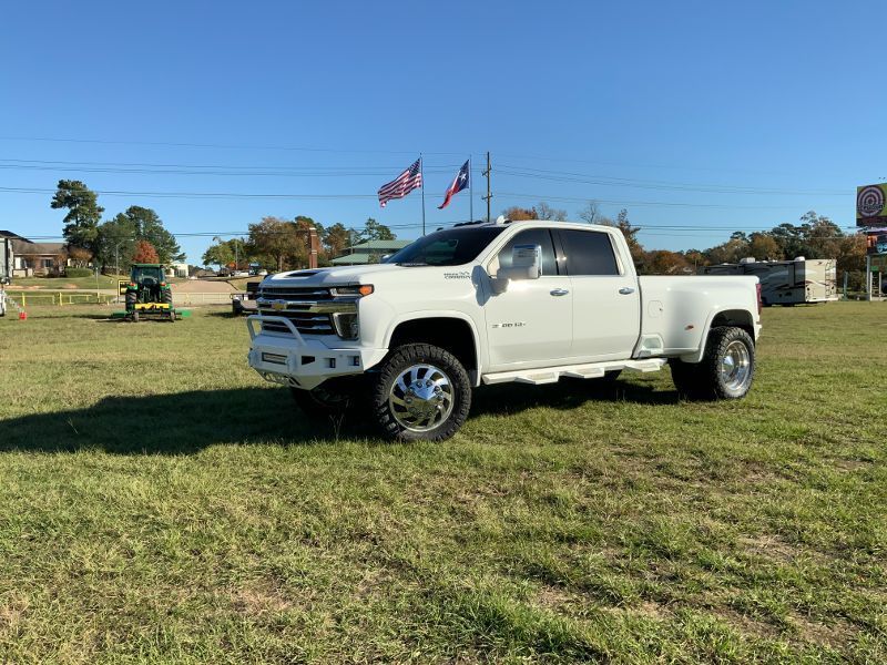 A white truck is parked in a grassy field.