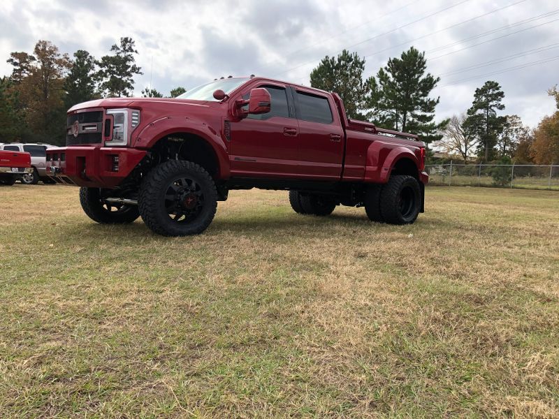 A red truck is parked in a grassy field.