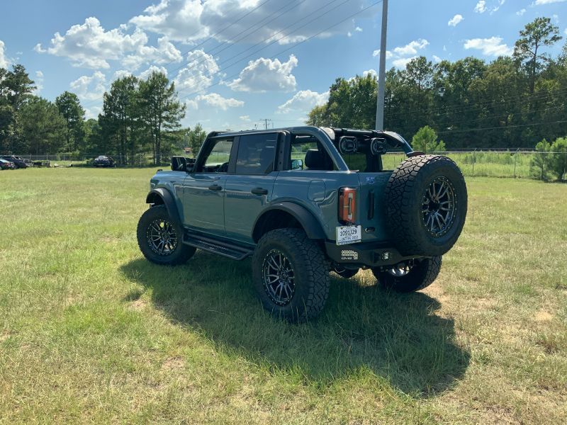A blue ford bronco is parked in a grassy field.
