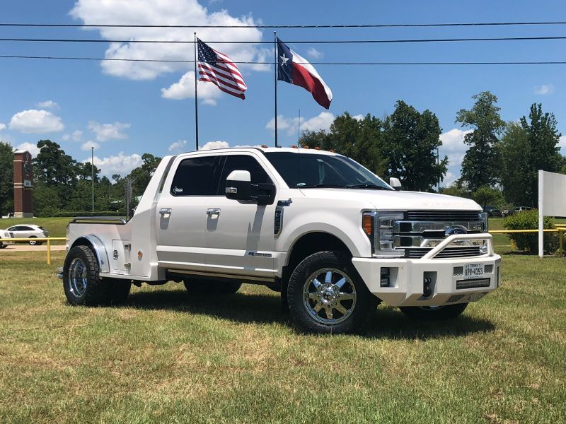 A white tow truck is parked in a grassy field.