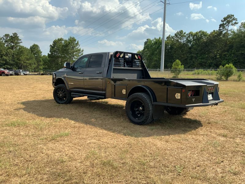 A truck with a flat bed is parked in a field.