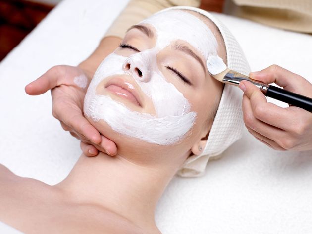 Facial treatment with white cream applied as a brush spreads product on a reclining client’s face