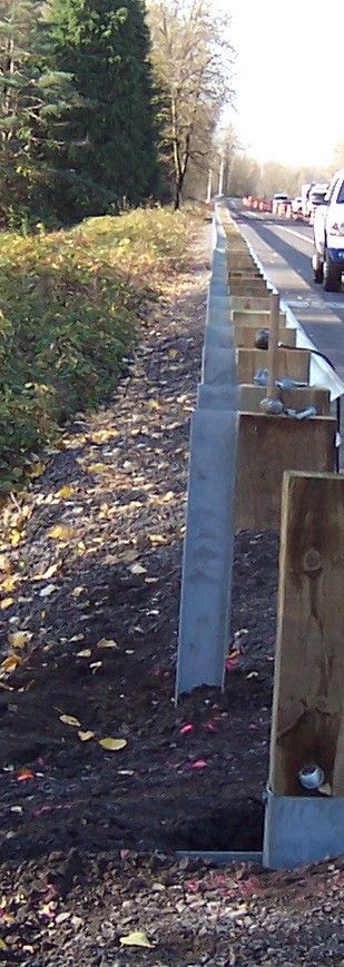 A wooden fence is being built next to a highway.