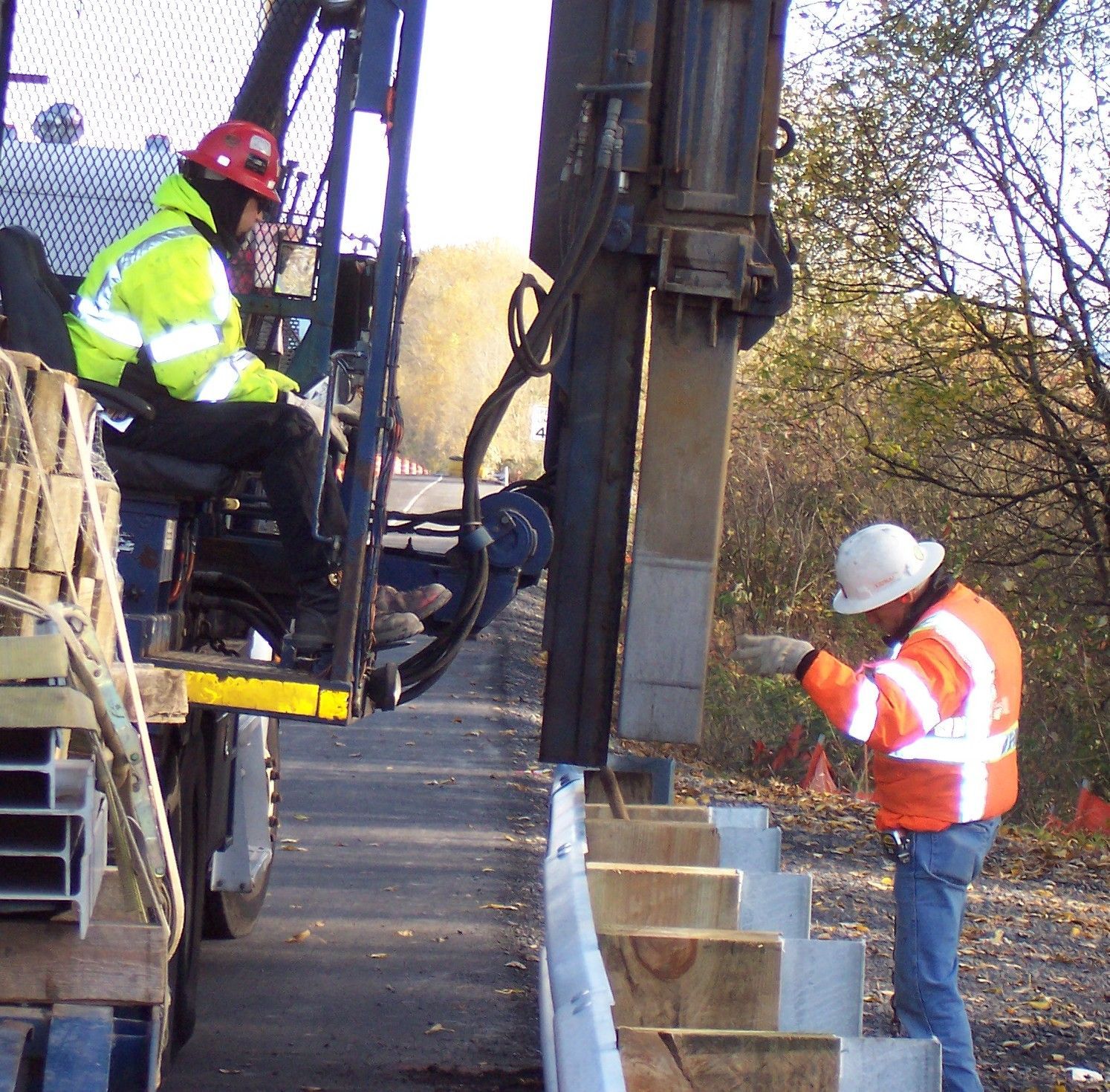 A man wearing a hard hat is standing next to a machine