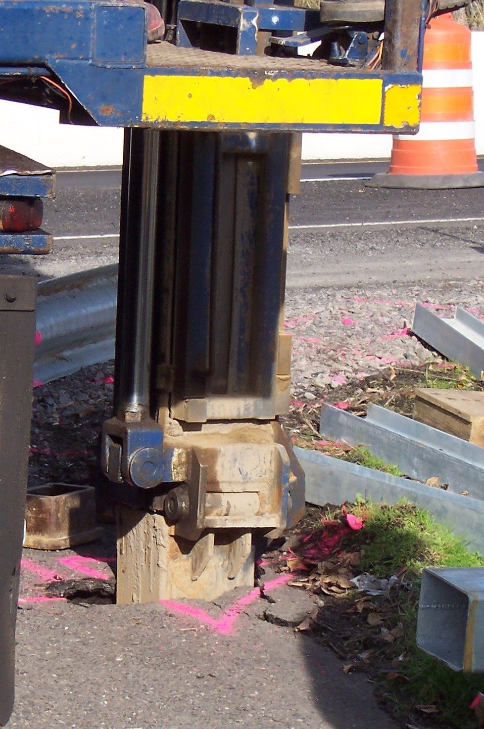 A blue and yellow machine is sitting on the side of the road