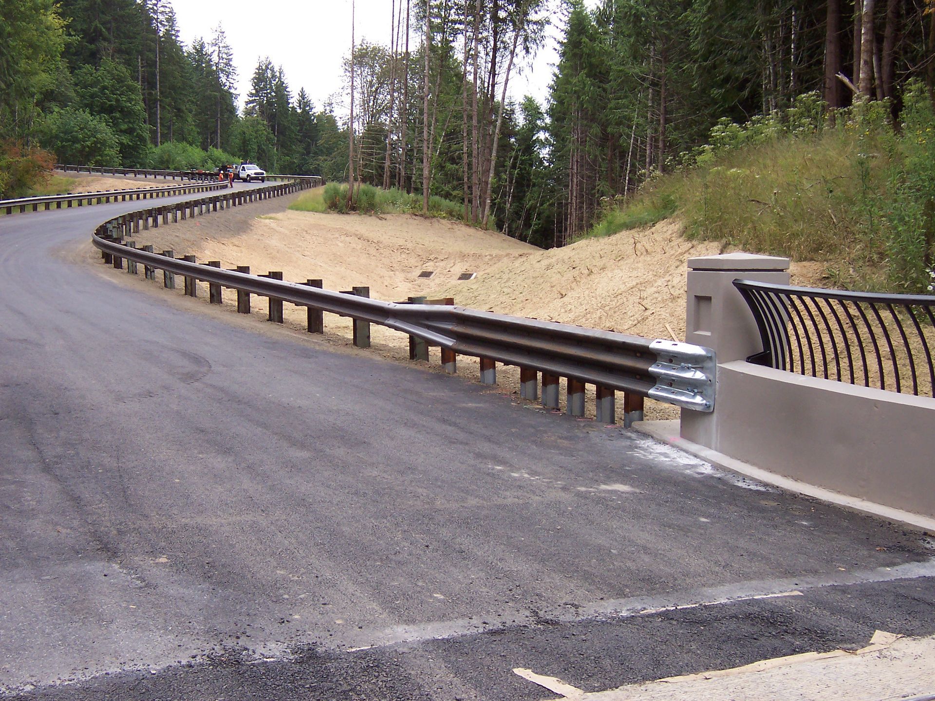 A curvy road with a railing on the side of it