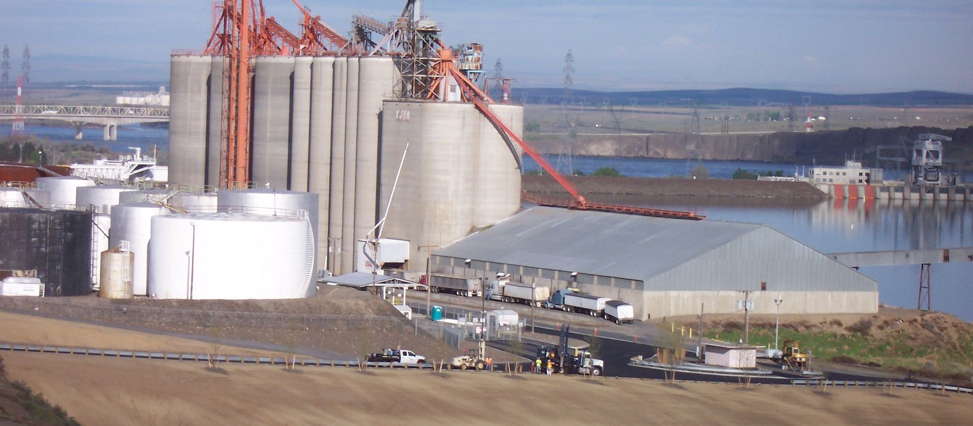 A large building with a lot of tanks in front of a body of water.