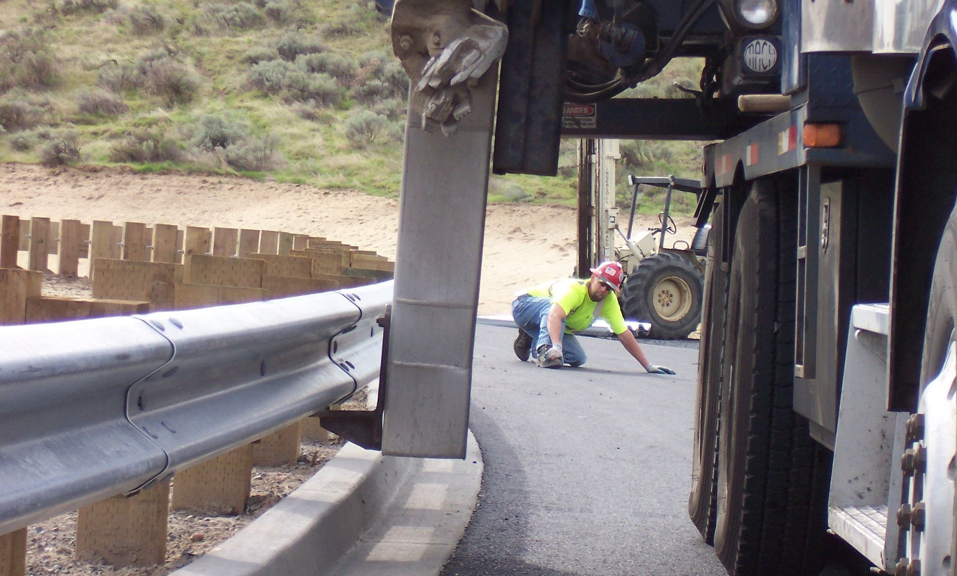 A man in a yellow shirt is kneeling next to a truck
