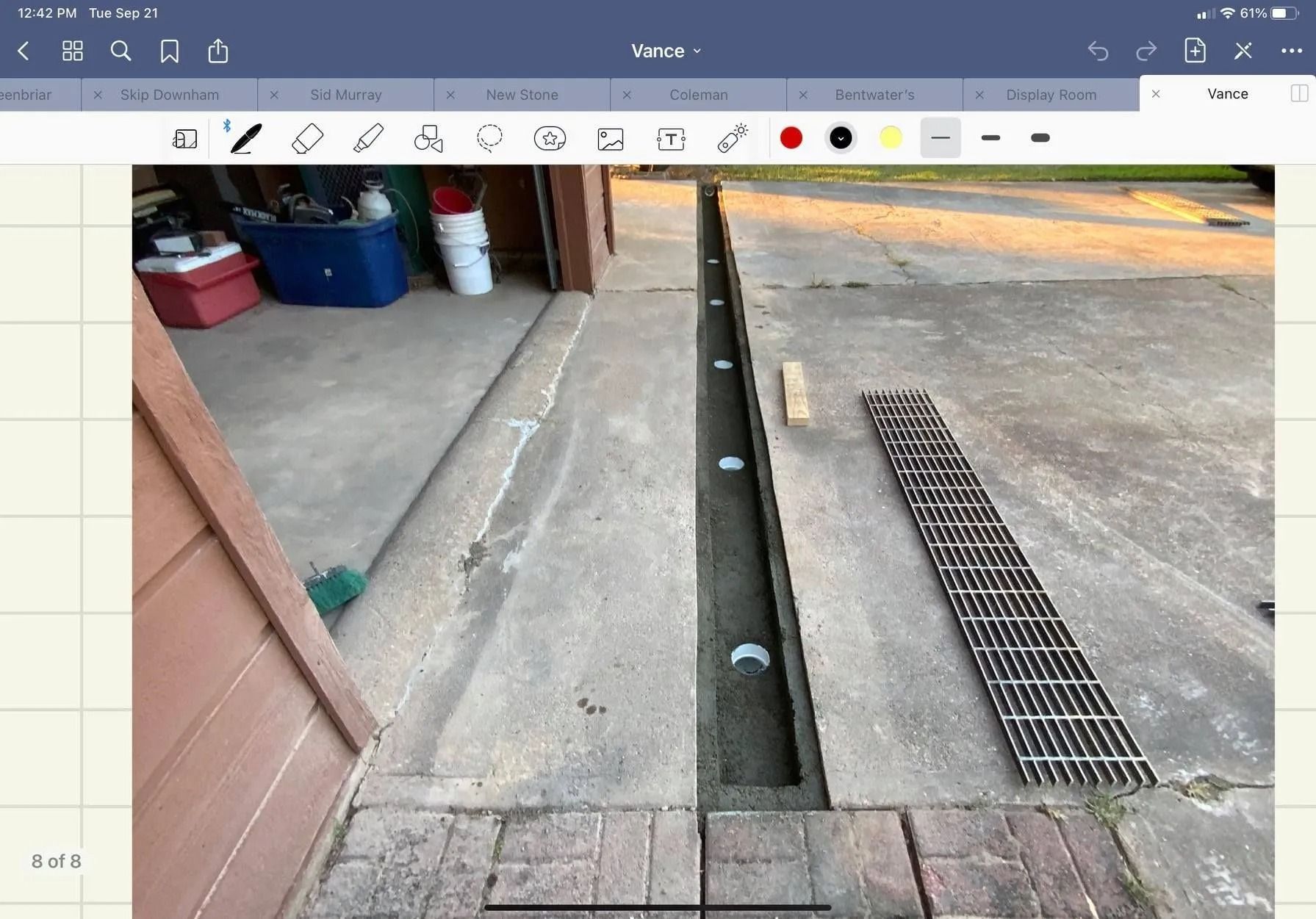 Concrete driveway with trench drain being installed, metal grate and brick edging.