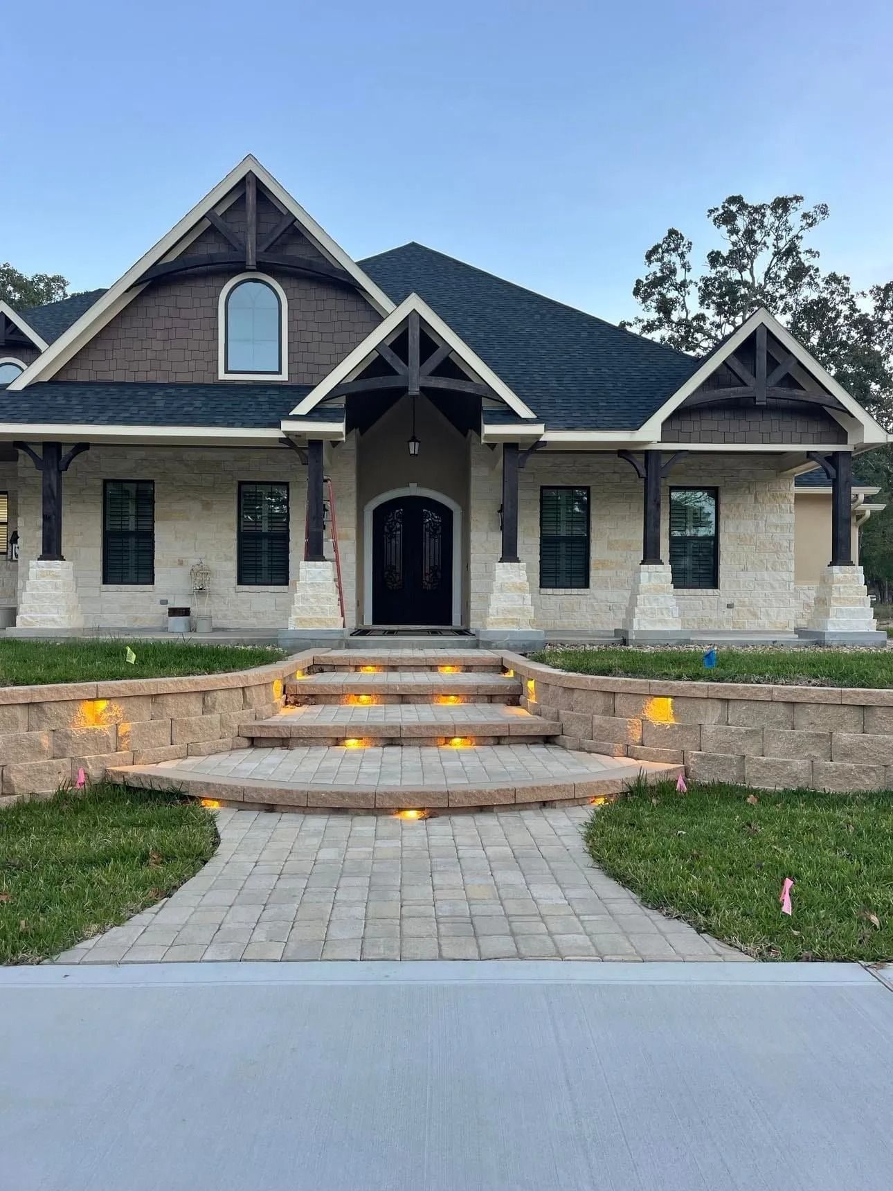 Exterior of a house with stone facade, steps, and landscaping. Dark roof and accents.