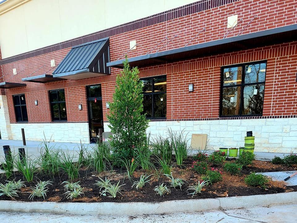 Building with brick facade, black-framed windows, and landscaping in front.