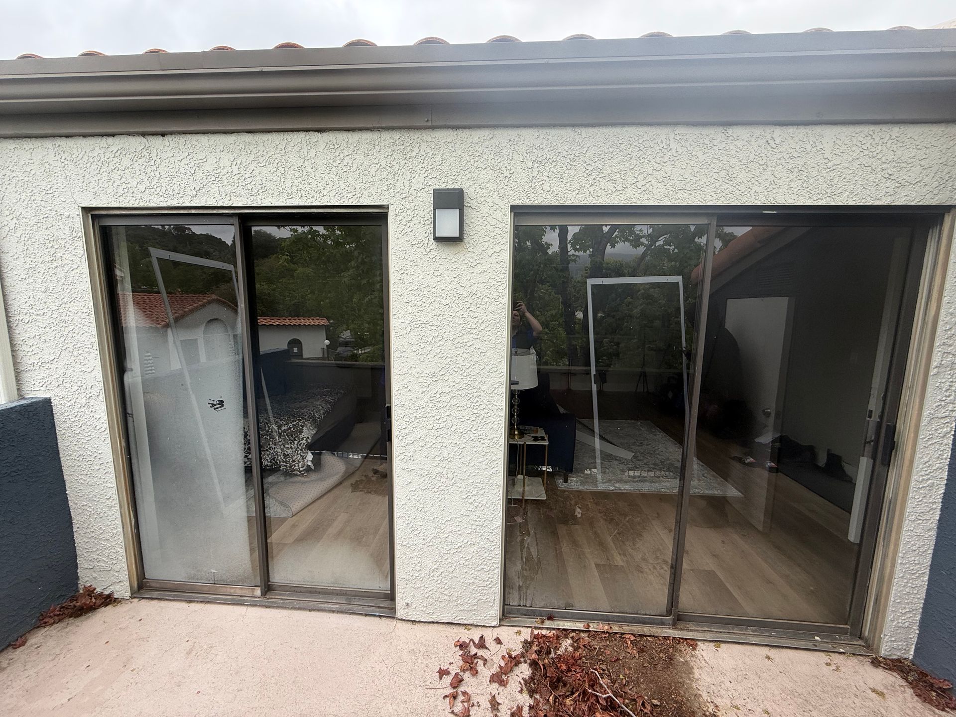Patio with sliding glass doors, one door open, showing a tiled interior and outdoor railing.