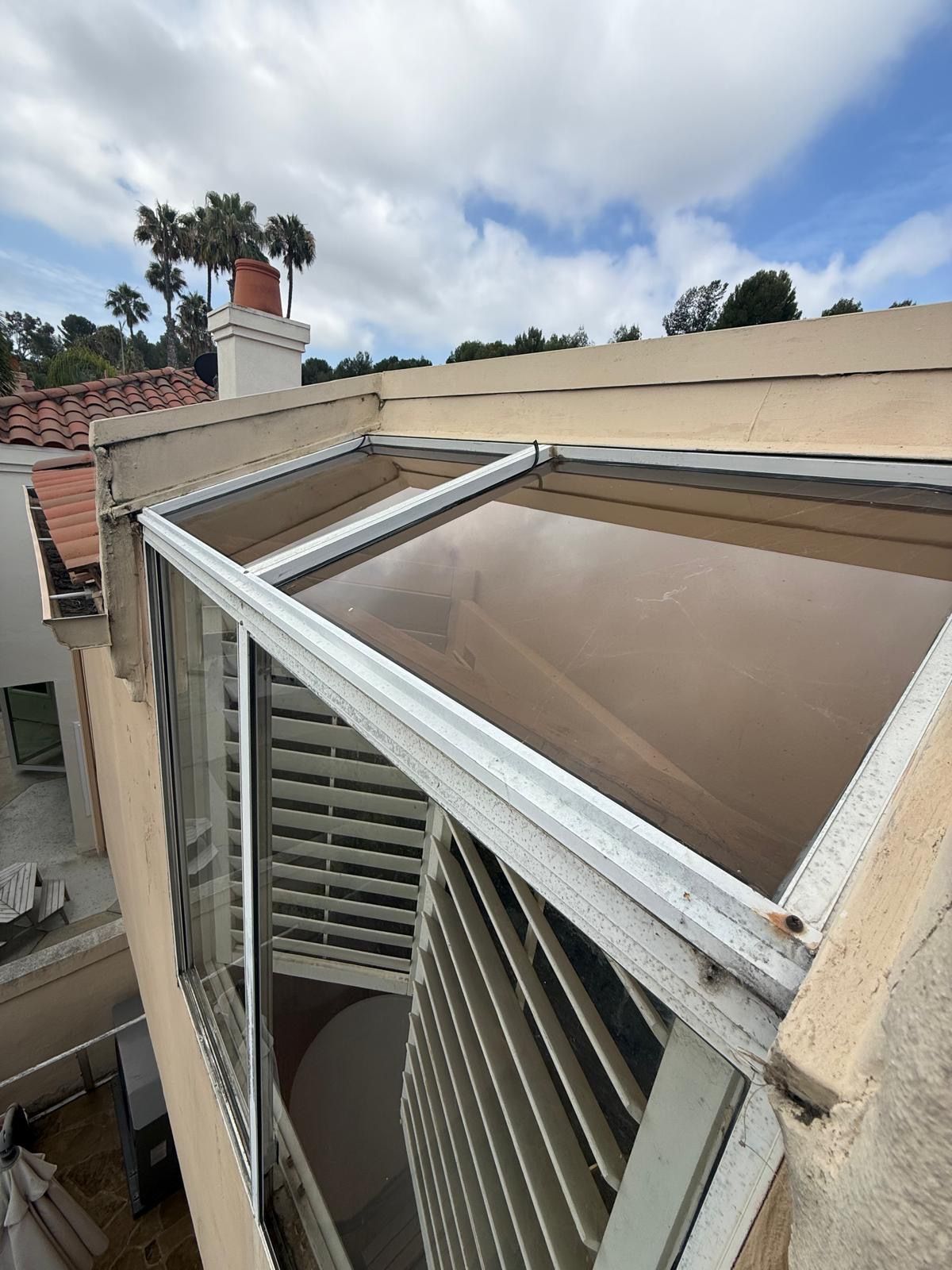 Open window awning with slatted shutters on a beige building exterior