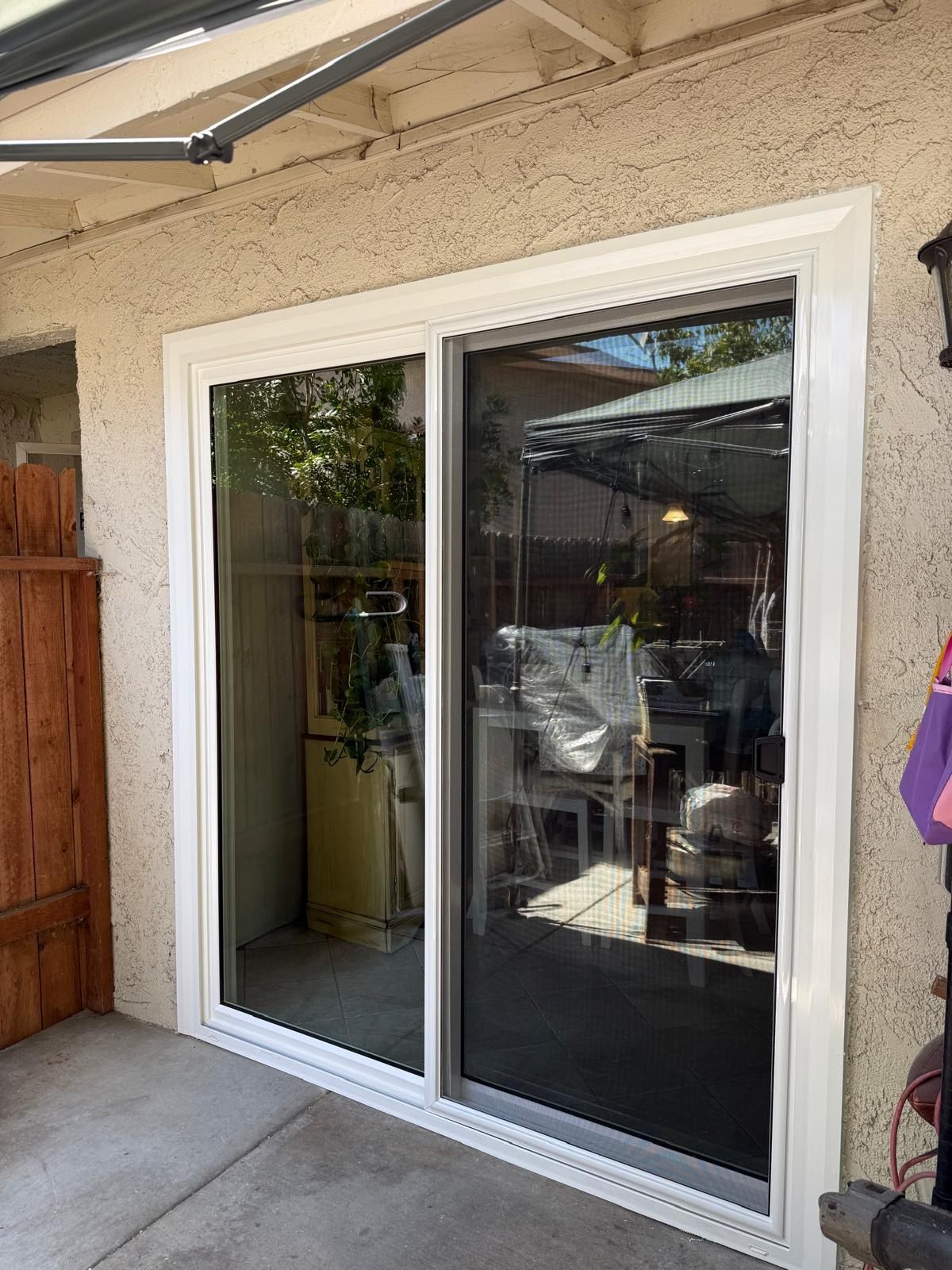 Sliding glass door with white frame and patio reflection on a stucco house exterior