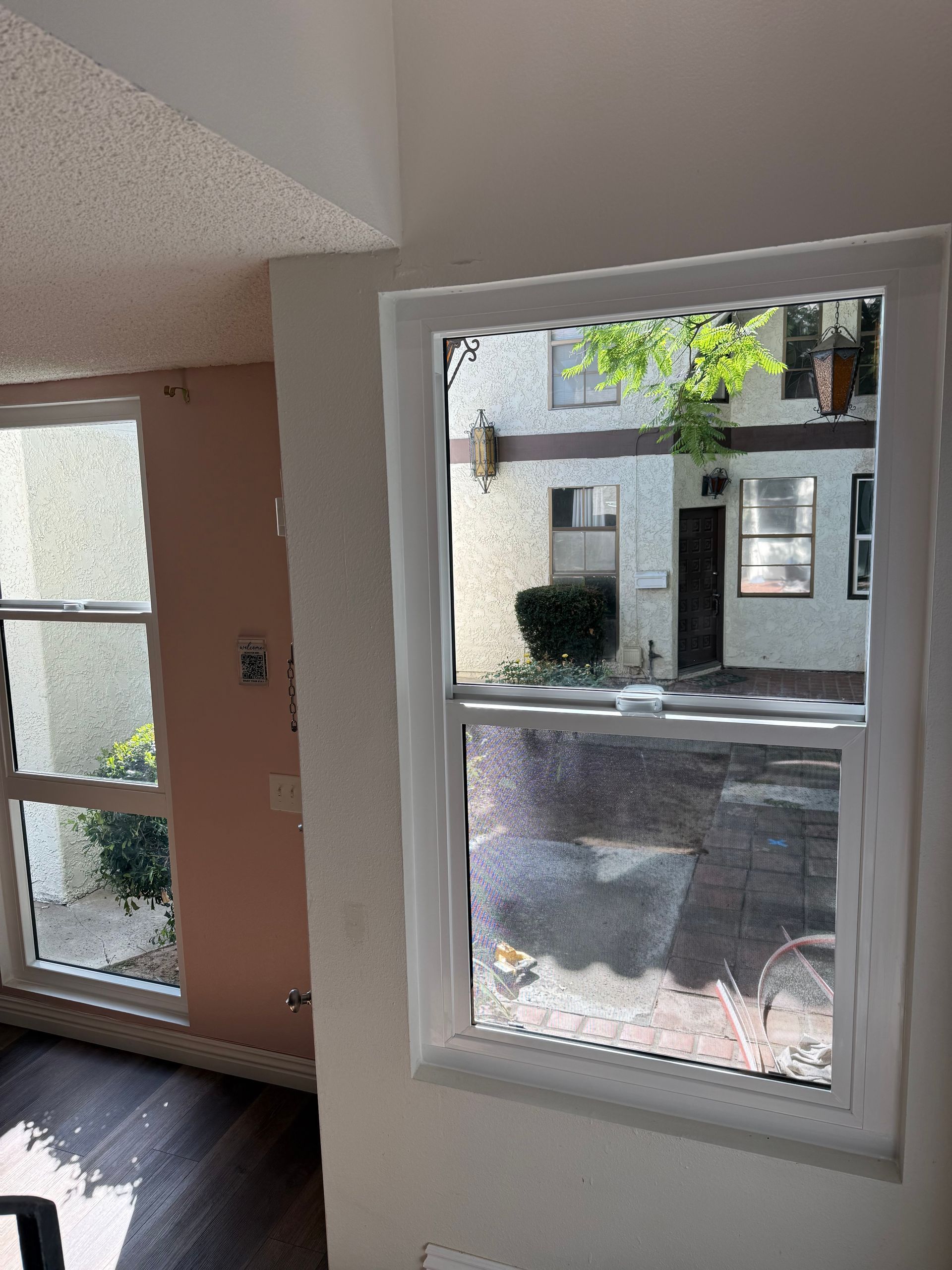 Interior view through a window into an apartment courtyard with trees and building entrances