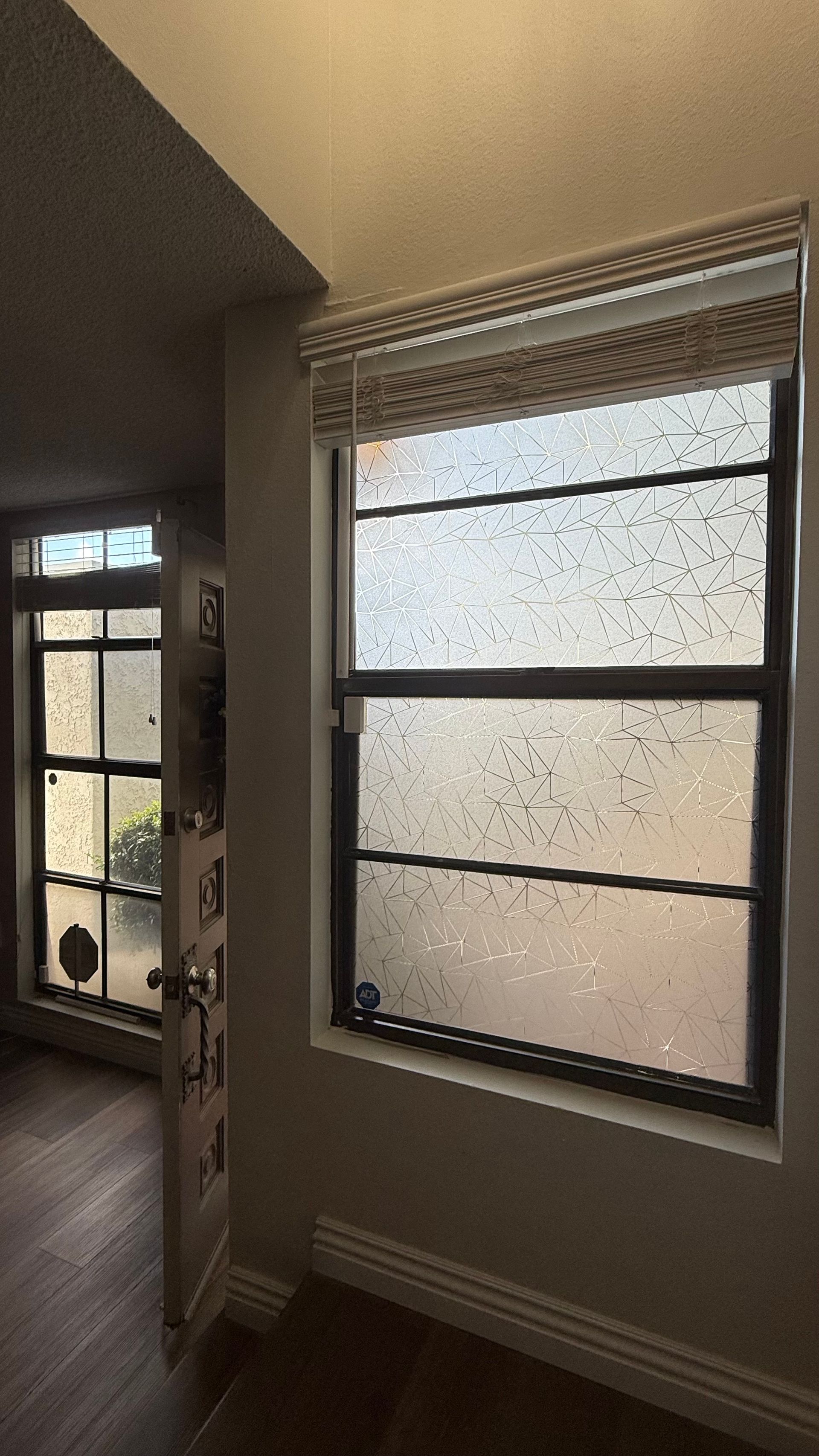 Hallway with a frosted window and blinds beside a doorway to another room