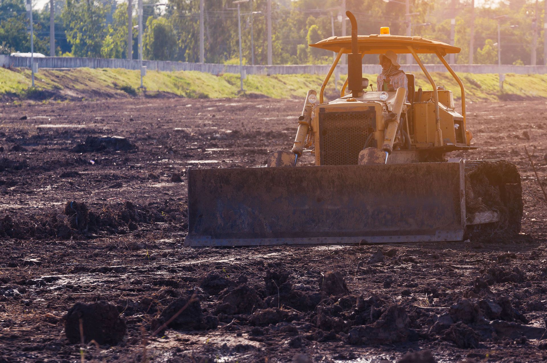 A bulldozer is moving dirt in a muddy field.