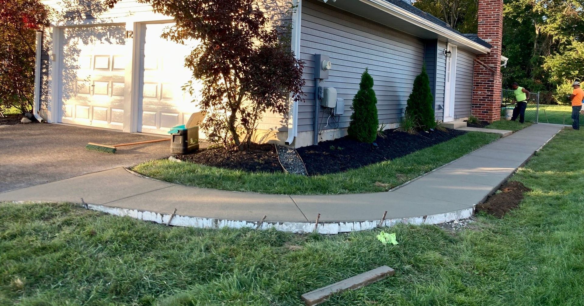 A group of people are working on a sidewalk in front of a house.