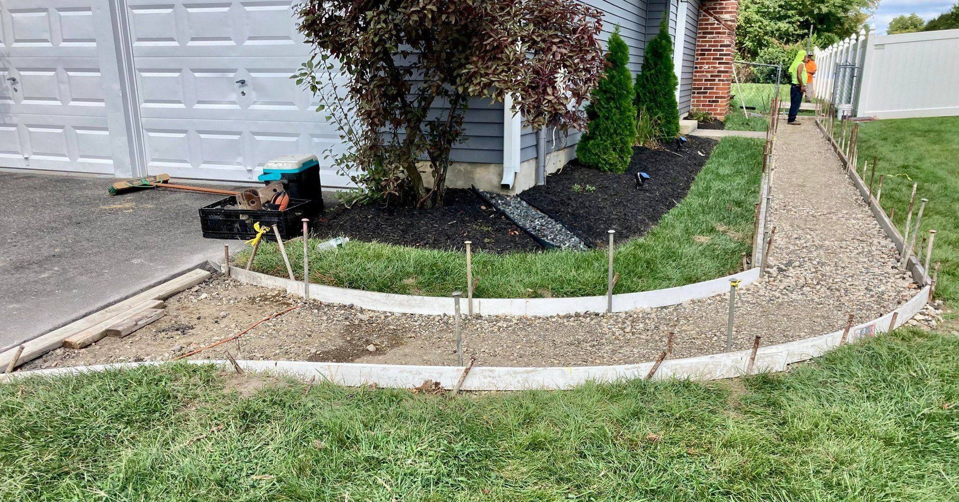 A concrete walkway is being built in front of a house.