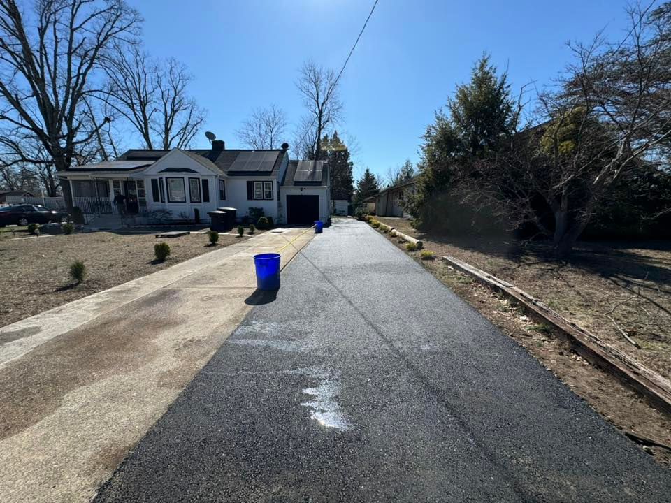 A driveway leading to a house with a blue bucket on the side of it.