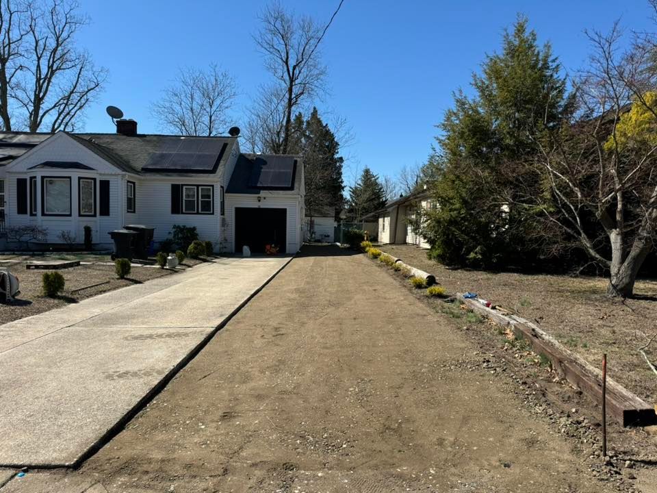 A concrete driveway leading to a white house