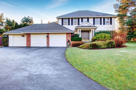 A large house with three garage doors and a driveway