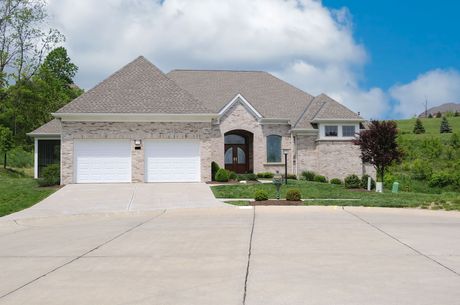 A brick house with two garage doors and a concrete driveway