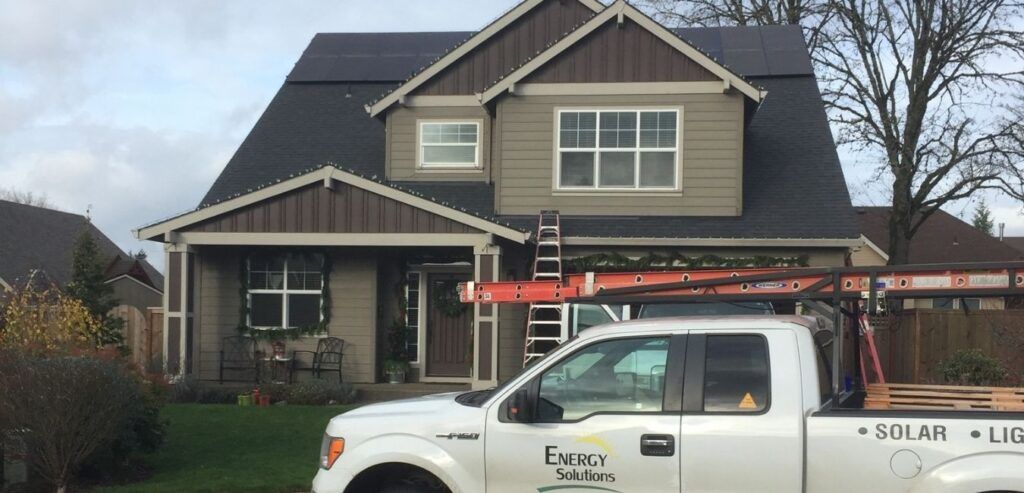 A house with solar panels on the roof and a white pickup truck in front.