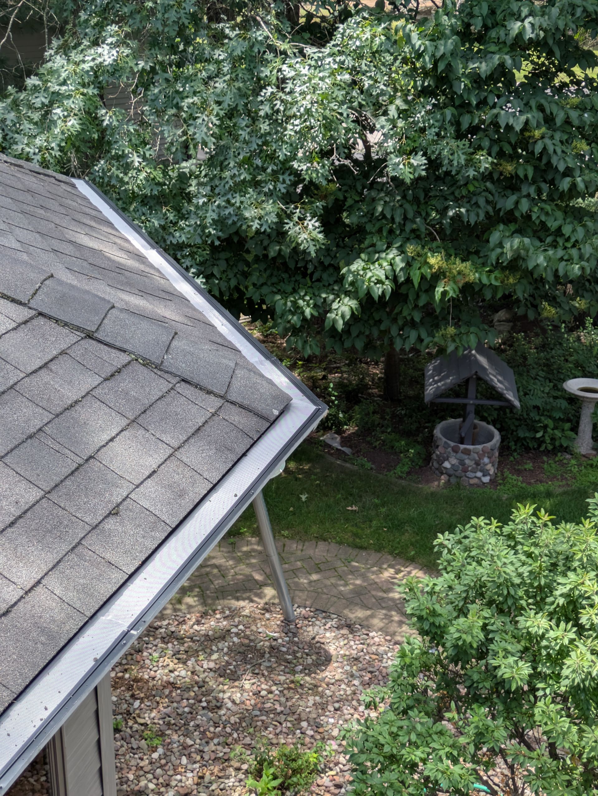 An aerial view of a roof with a gutter and trees in the background.