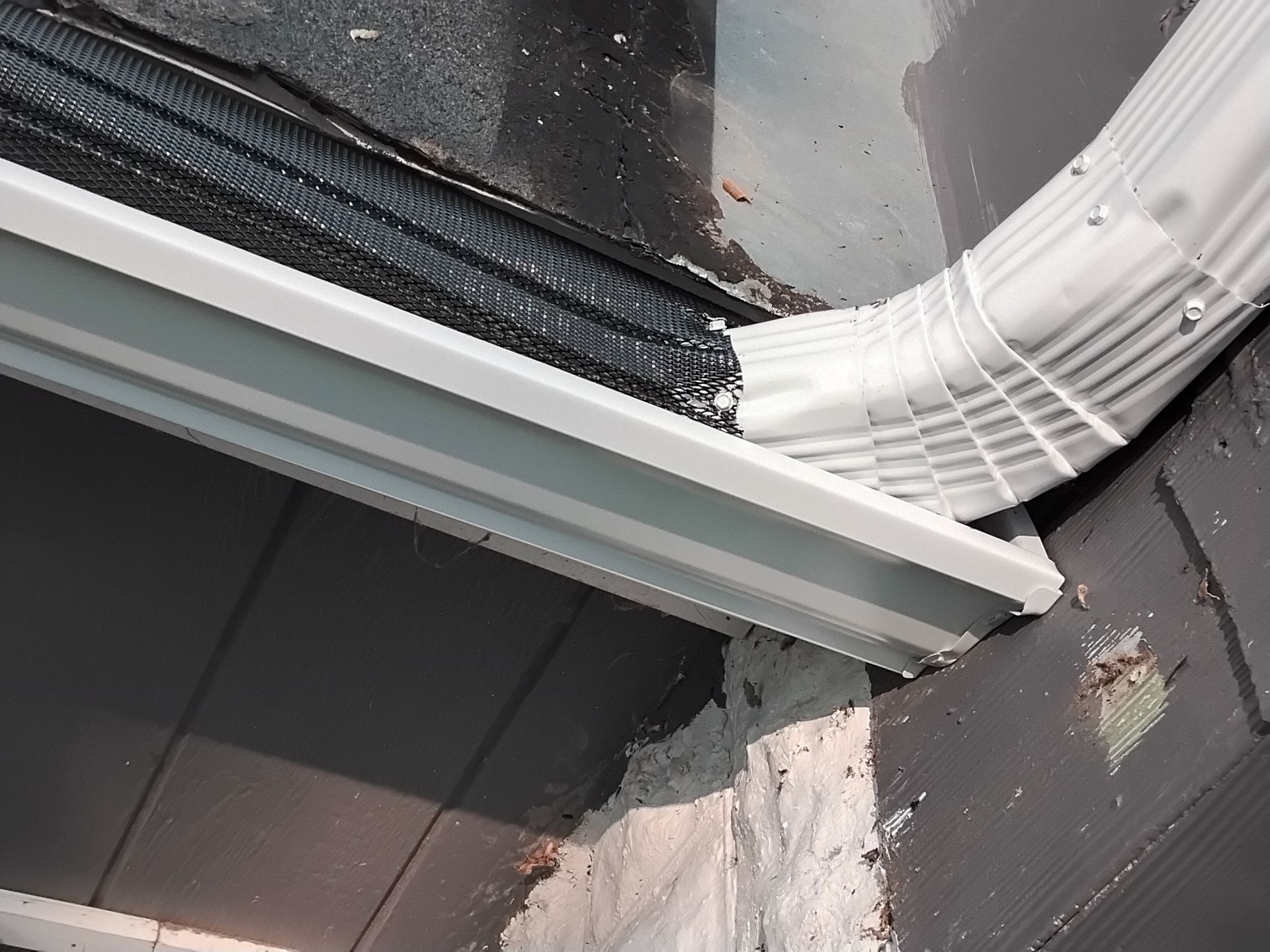 A white gutter is attached to the side of a building