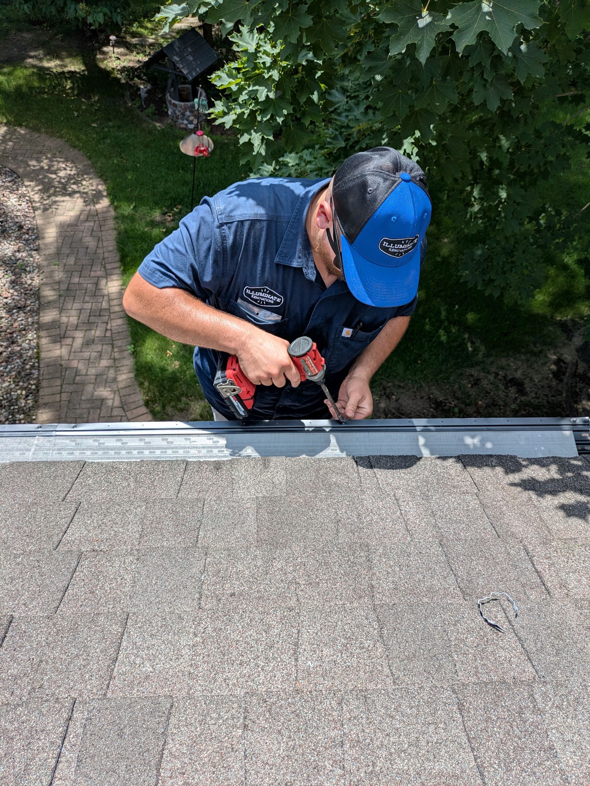 A man is working on a roof with a drill.