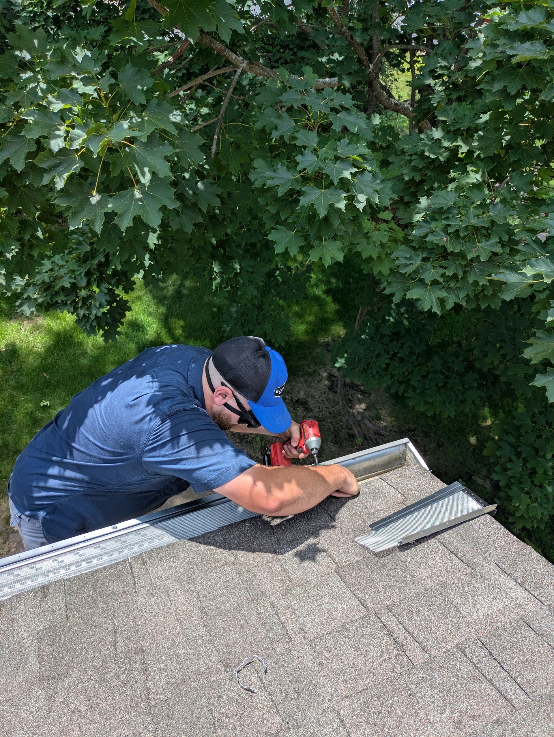 A man is working on a roof with a drill.