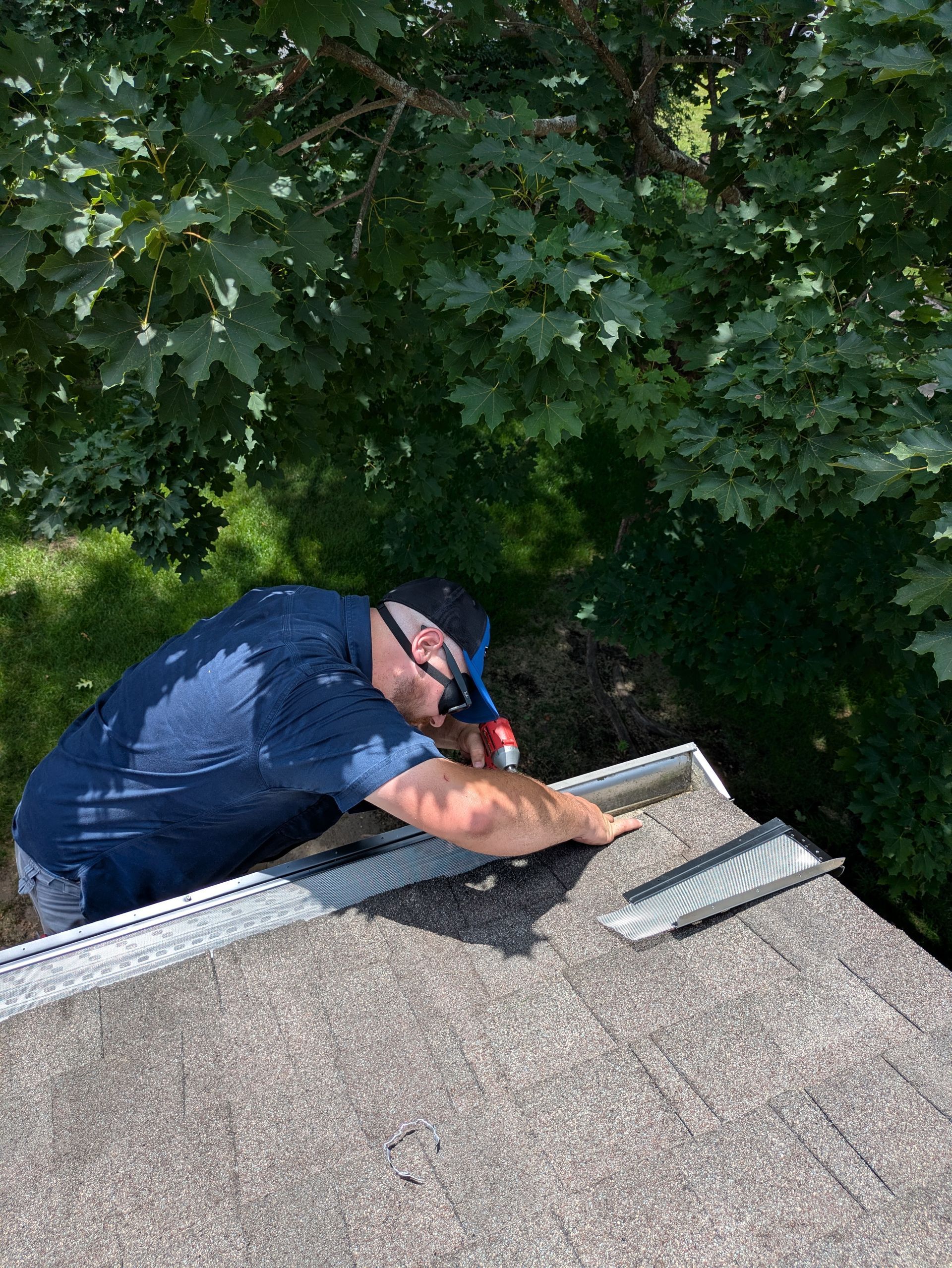 A man is working on a roof with a flashlight.