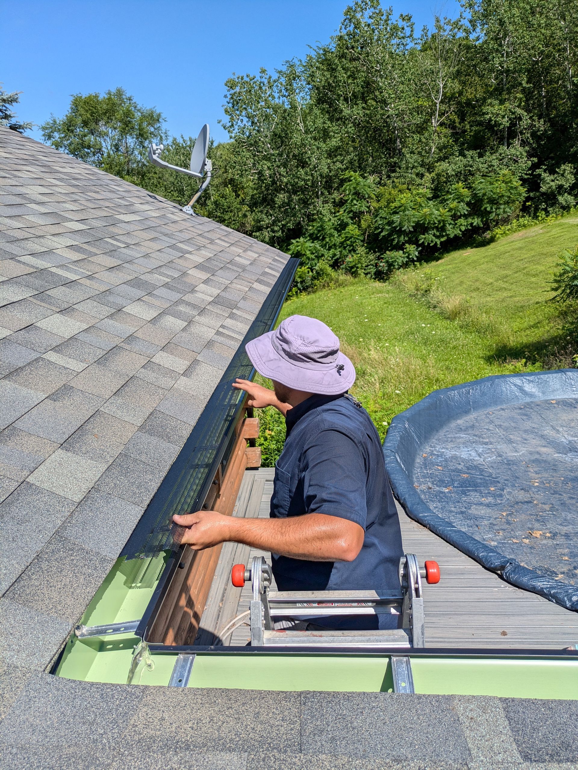 A man is standing on a ladder on top of a roof.